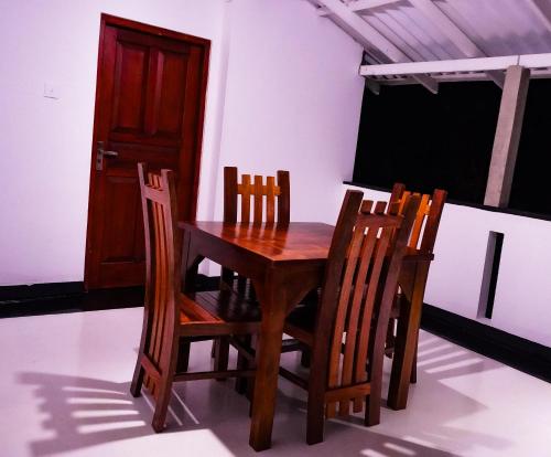 ein Holztisch mit vier Stühlen und einer Tür in der Unterkunft K siri Holiday Home in Balapitiya