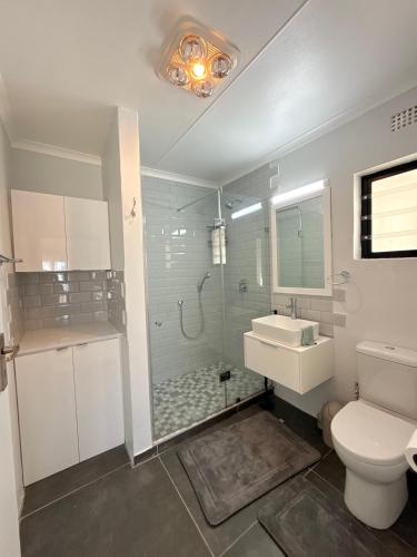 a bathroom with a shower and a toilet and a sink at Corner Rock in Stompneusbaai