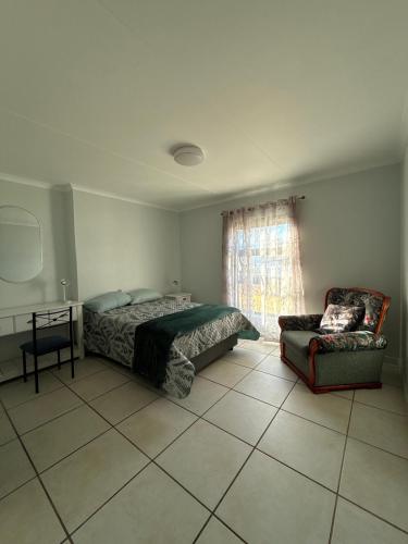 a bedroom with a bed and a chair and a window at Corner Rock in Stompneusbaai