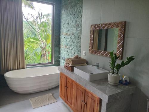 un bagno con vasca, lavandino e specchio di The Samudra Ubud Villa ad Ubud