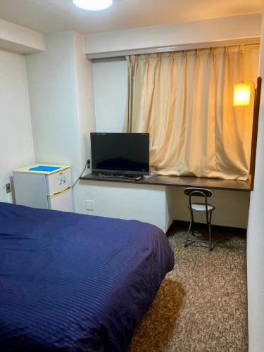 a bedroom with a bed and a desk with a laptop at 十五町目ag in Iwaki