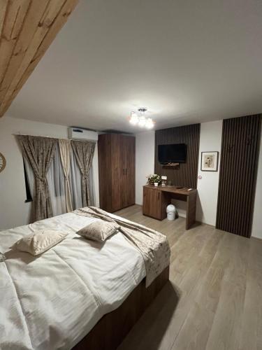 a bedroom with a large bed and a desk at Vila Soleil in Azuga