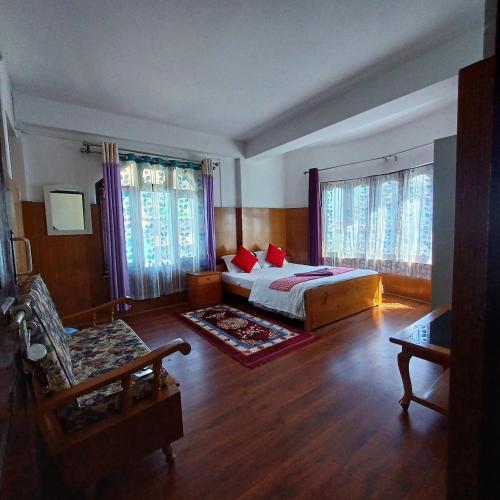 a bedroom with a bed and two windows at Mandrelling Inn in Tawang
