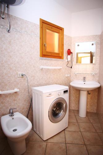 a bathroom with a washing machine and a sink at Appartamenti Ideal in Isola Rossa