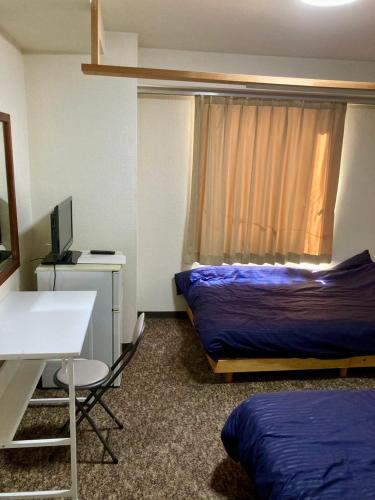 una habitación con una cama y un escritorio con una computadora en 十五町目ag, en Iwaki