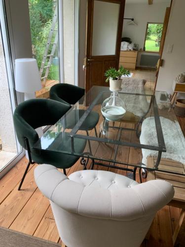einen Glastisch und Stühle im Wohnzimmer in der Unterkunft L Orée du Bois in Agnetz