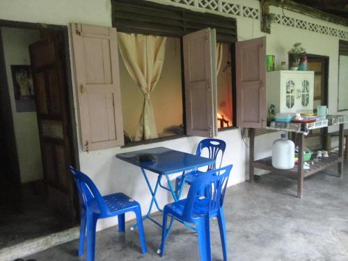 einen Tisch und zwei blaue Stühle in einem Zimmer in der Unterkunft Grandma's Home Sangkhlaburi in Sangkhla Buri