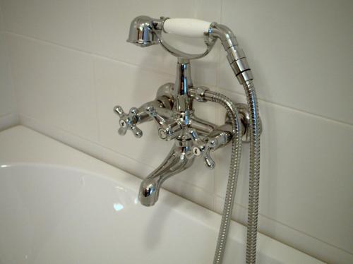 Hay un cabezal de ducha junto a la bañera. en Hotel Vorsen, en Gingelom
