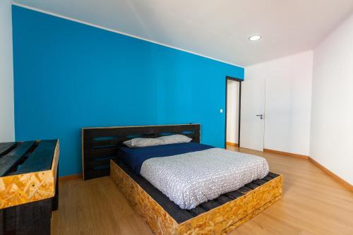 a bed in a room with a blue wall at The Pallet - Guest House in Santa Cruz