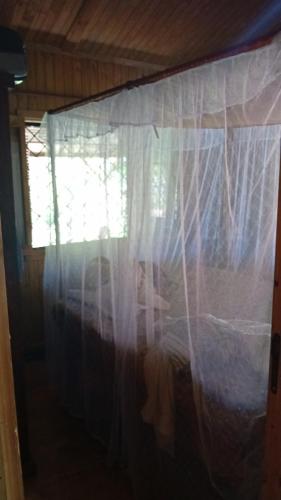 una camera da letto con un letto e una finestra con tende di Danae Beach Golf a Nosy Be