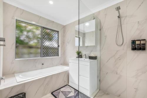 a white bathroom with a tub and a sink at 3 Bedroom Fully Renovated Home away from Home in Brisbane