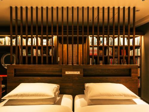two beds in a room with a book shelf at Richmond Hotel Premier Tokyo Schole in Tokyo