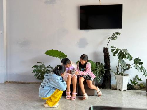 Tres chicas sentadas en un sofá mirando una planta. en A La Mer Măng Đen, en Kon Plong