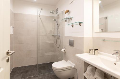a bathroom with a shower and a toilet and a sink at Aparthotel Waterkant Suites - Fewos am Meer mit SPA in Börgerende-Rethwisch