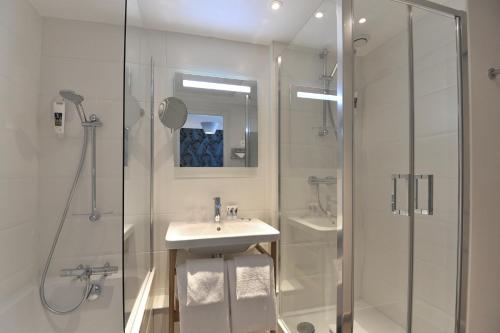 a white bathroom with a sink and a shower at Mercure Paris Saint Cloud Hippodrome in Saint-Cloud