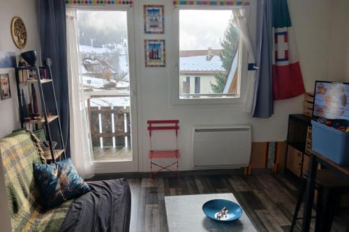 een woonkamer met twee ramen en een tafel bij Les Chamoix en Chartreuse in Saint-Pierre-de-Chartreuse