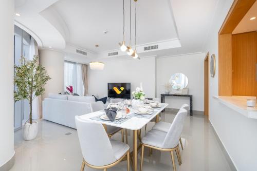 a dining room and living room with a white table and chairs at Vogue Vacation Homes, Downtown Opera Grand near Burj Khalifa and Dubai Mall, Two Bedroom Apartment with Large Balcony and Access to all Amenities in Dubai
