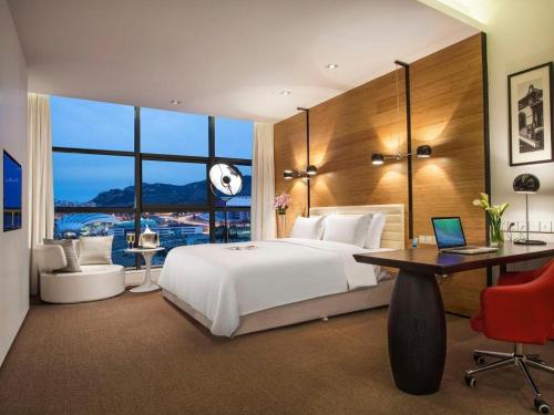 um quarto com uma cama grande e uma secretária com um computador portátil em Himalayas Qingdao Hotel em Qingdao
