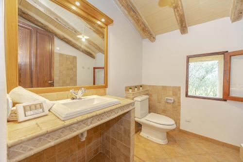 un bagno con lavandino, WC e specchio di Villa Can Granot a Caʼs Concos