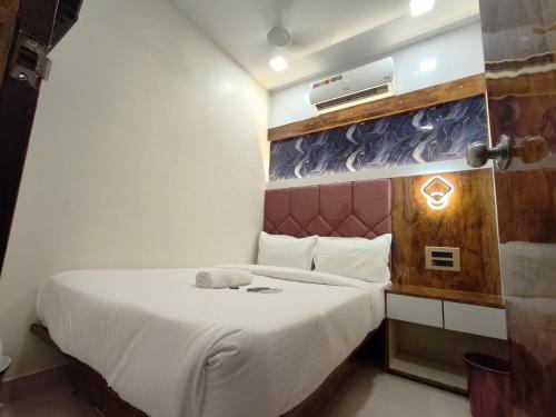 a small bedroom with a bed with white sheets at Hotel M R STAY in Mumbai