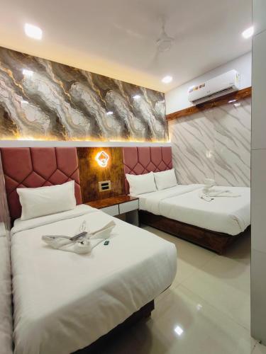 a hotel room with two beds and a wall with a painting at Hotel M R STAY in Mumbai