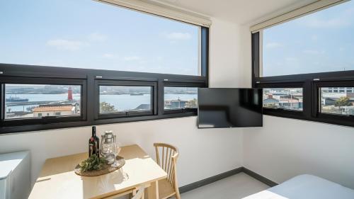 Zimmer mit einem Tisch und einigen Fenstern in der Unterkunft Yeosu Nangmanstay pension in Yeosu