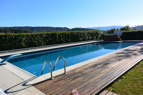 a swimming pool with a wooden boardwalk next to at Casa do Lagar in Alvarenga