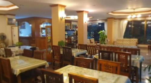 a restaurant with tables and chairs in a room at Ritzy House Hotel in Na Dhung