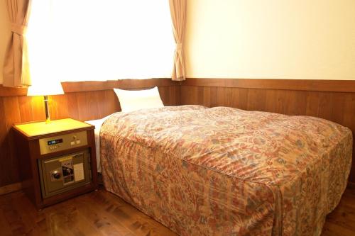 a bedroom with a bed and a table with a lamp at Rakuchin in Naha
