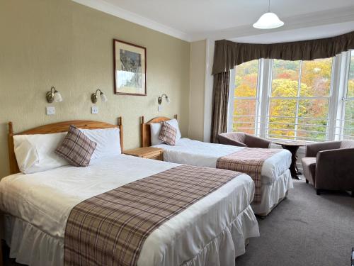 a hotel room with two beds and a window at The Hand Hotel Llangollen by Compass Hospitality in Llangollen