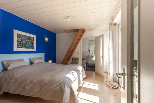 Un dormitorio con una pared azul y una cama en Btween Maas & Waal, en Druten