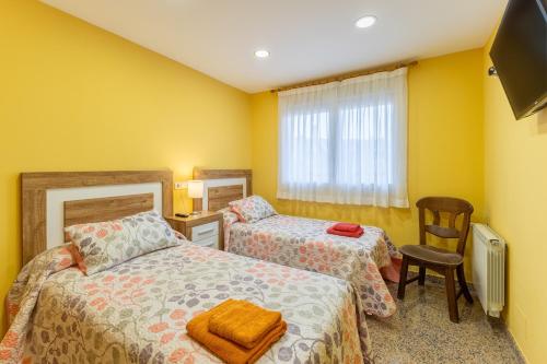 1 dormitorio con 2 camas, TV y silla en Magnifico, en Pozuelo de Alarcón