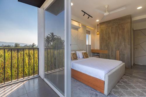 a bedroom with a bed and a balcony at SaffronStays Palash in Ane