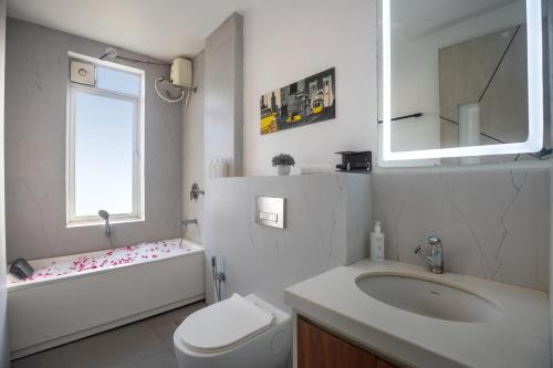a bathroom with a sink and a toilet and a window at SaffronStays Palash in Ane