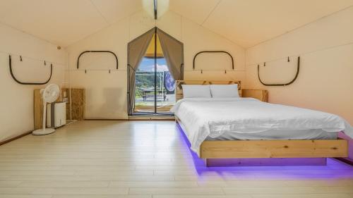 a bedroom with a large bed with purple lighting at Gapyeong Cheongchun Glamping & Caravan in Gapyeong