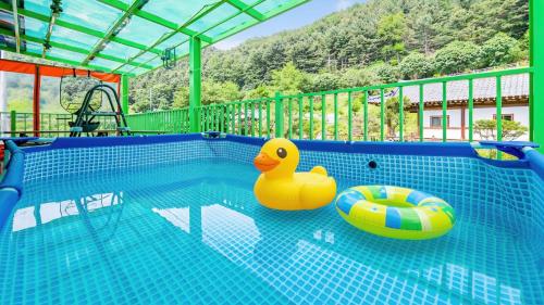 a swimming pool with two rubber ducks and a float at Gapyeong Yeoul kids pension in Gapyeong