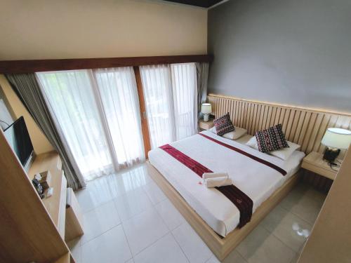 a bedroom with a large bed in a room with windows at Surya Pandawa Homestay in Uluwatu