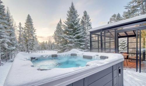 a jacuzzi tub in the snow next to a house at Spa - Waterfront - Le Nordika in Valcartier Station