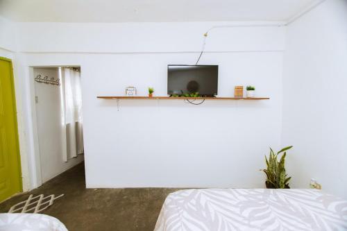 a white room with a bed and a tv on a wall at Departamento centrico con estacionamiento WiFi in Matamoros