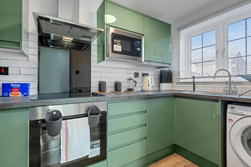 a kitchen with green cabinets and a washing machine at 4 Bedroom Family & Contractor House in Colwick, Nottingham - Sleeps 8 - By CircleWay Homes in Nottingham