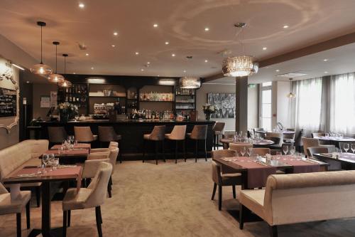 a restaurant with tables and chairs and a bar at Mercure Paris Saint Cloud Hippodrome in Saint-Cloud