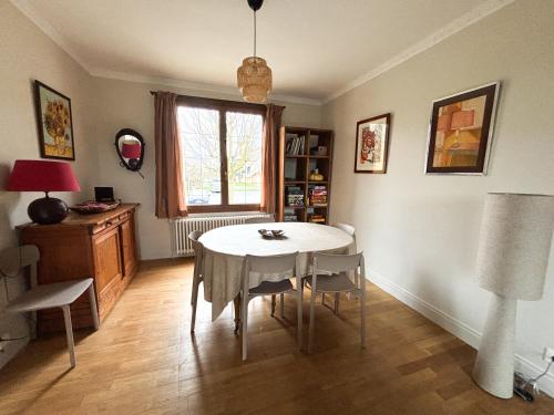 ein Esszimmer mit Tisch und Stühlen und einem Fenster in der Unterkunft Maison avec jardin dans le centre de Cabourg in Cabourg