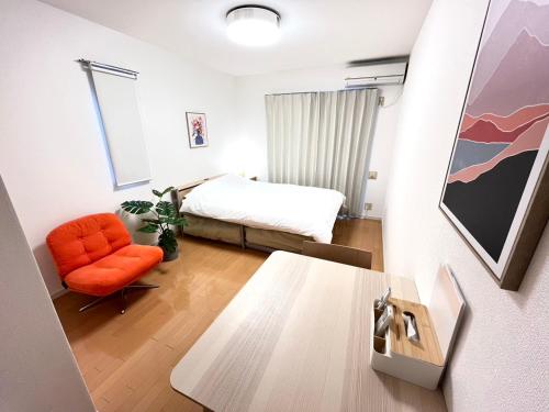 een slaapkamer met een bed en een oranje stoel bij Camelot House 南福岡 in Fukuoka