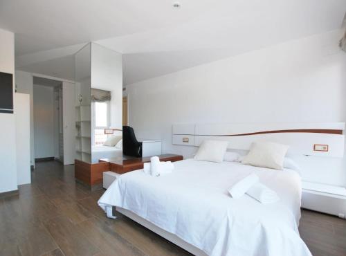 a white bedroom with a white bed and a desk at Rey apartment in Vilassar de Mar