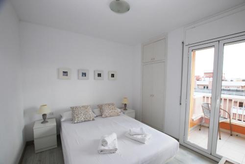 a white bedroom with a bed and a large window at Narciso views in Vilassar de Mar