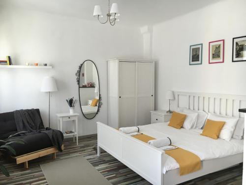 a white bedroom with a bed and a mirror at FLH - Studio Mai cu aroma de cafea si ceai in Sibiu