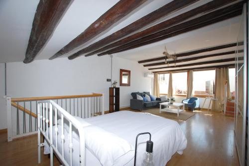 a bedroom with a white bed and a living room at Cami Ral in Premiá de Mar
