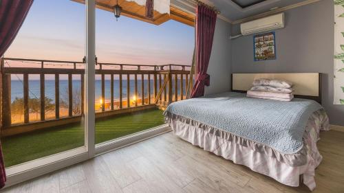 a bedroom with a bed and a large window at Ganghwa Badatgashimteo Pension in Incheon