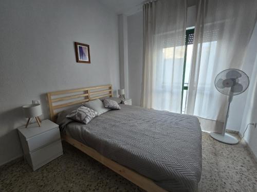 - une chambre avec un lit et une fenêtre avec un ventilateur dans l'établissement Apartamento LOS BALCONES DE BARBATE, à Barbate