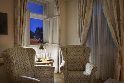 Una sala de estar con dos sillas y una ventana. en Hotel At the Golden Scissors, en Praga